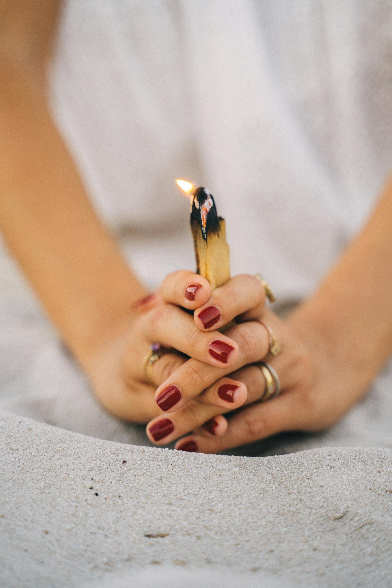 Close-up of hands with palo santo stick, symbolizing relaxation and mindfulness.